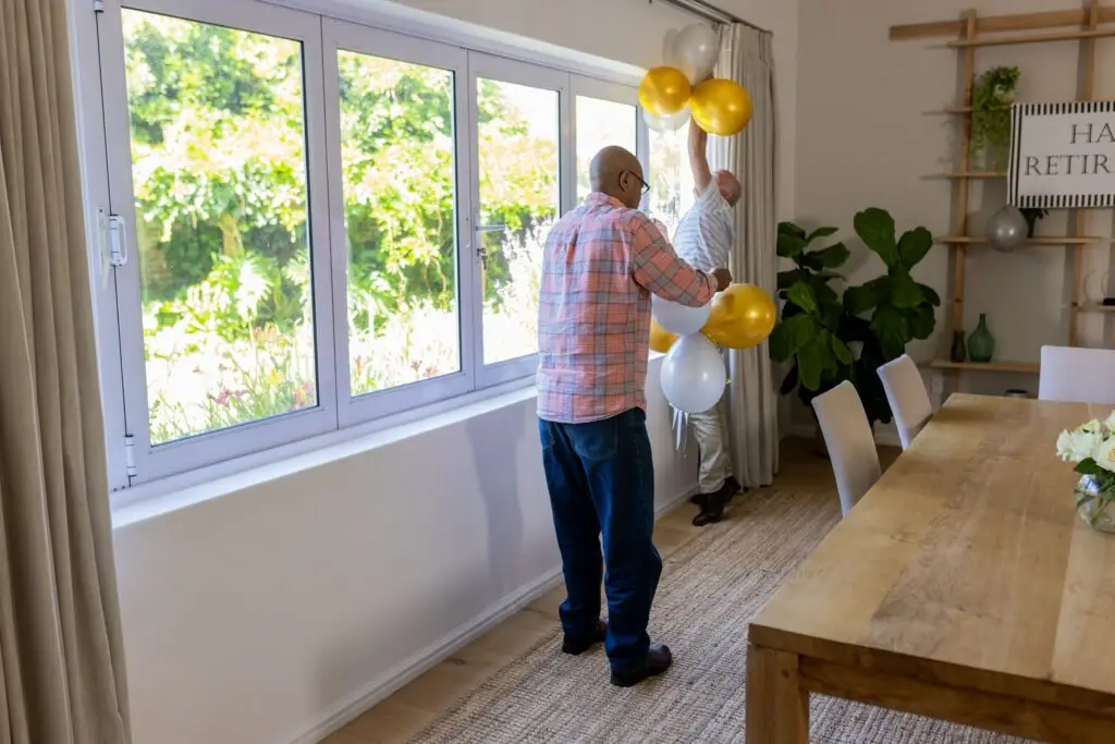 Senior friends decorating room with balloons for retirement celebration at home